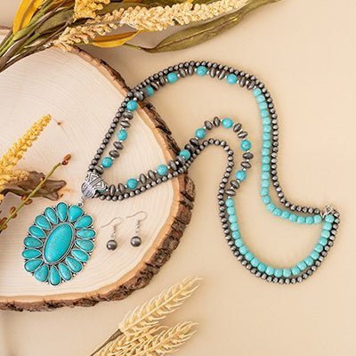 Introducing the stunningly stylish Can't Squash Me Necklace, featuring 32" of exquisite double-stranded craftsmanship with a 3" squash blossom pendant and elegant white crackle beads, copper multi size beads, and a stamped Aztec pendant connector. For a unique look, select the turquoise option, with turquoise crackle beads and multi size Navajo pearls. Perfect for the trendsetter who appreciates a touch of luxurious exclusivity.