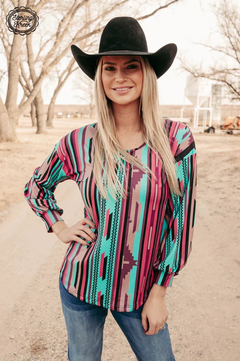 "Unleash your inner angelic style with this playful Porch Swing Angel Top! The stunning blend of pink, purple, turquoise, black and tan serape adds a touch of whimsy to this long sleeve top. Perfect for any occasion, this top is sure to make you the talk of the town!"  96% POLYESTER 4% SPANDEX