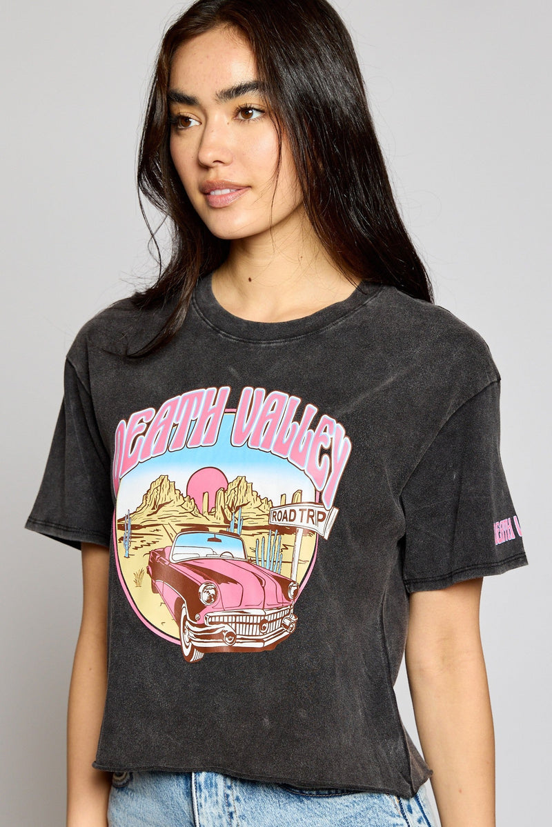 Take your wardrobe to the desert in our Death Valley Crop Top! This mineral-washed dark grey crew neck top has a raw hem and a unique desert graphic of a vintage car printed in pink. So don't just stand there, the sun's beating down - grab your Death Valley Crop Top and hit the road!