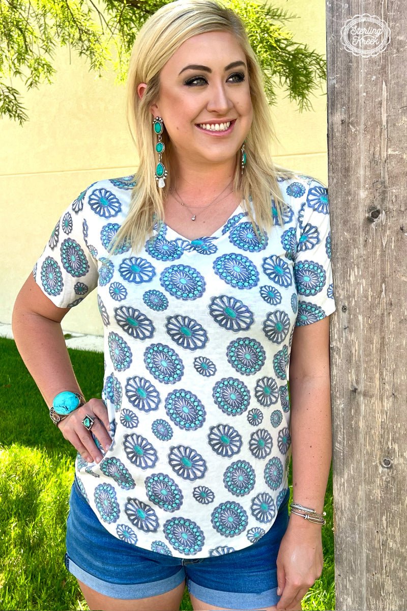 Take your style to the great, wild West with the PLUS Concho City Top! This stylish white vneck top is embellished with shiny conchos all over, giving your look a touch of cowgirl chic! Pop it on for an evening out or sunday brunch and turn heads everywhere you go! Yee-haw!  55% cotton 40% polyester 5% spandex   Measurements are with shirt laid flat   Meredith is wearing a Medium