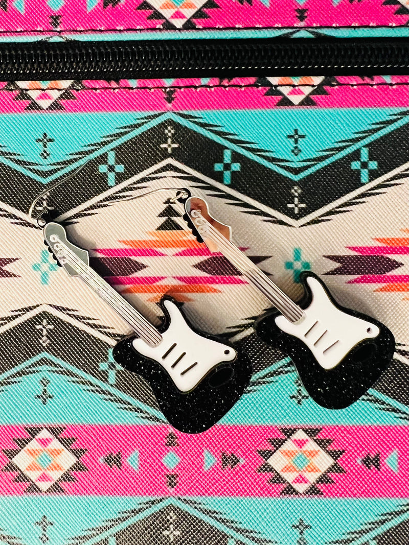 Strum your style with these cool 'Let's Rock N Roll' Guitar Earrings! Featuring a classic black and white guitar with shimmering silver detail, accented by extra sparkle from a touch of glitter. Perfect for any music lover, these earrings are sure to make a rockin' statement – 2 1/2" of dangle-y fabulousness!