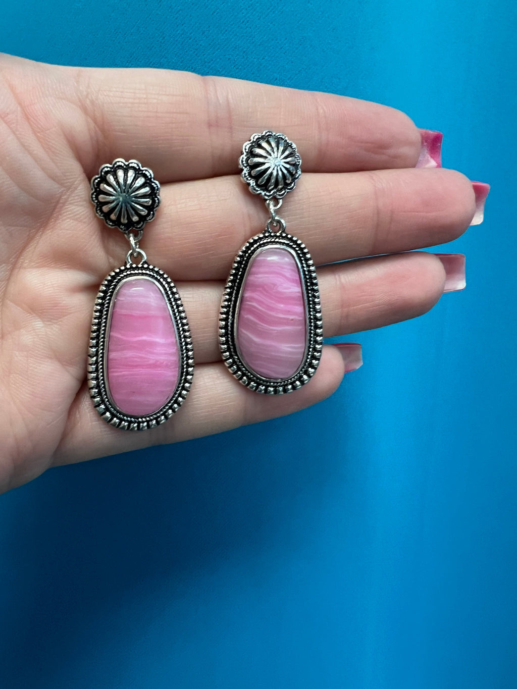 how off your Lone Star State pride with these chic Texas Rose Earrings! Made with polished silver and western-style concho, these dangly and elegant earrings feature an oval-shape, pink stone center for a touch of blushing color. Don't miss out on these two-inch stunners! Yeehaw!