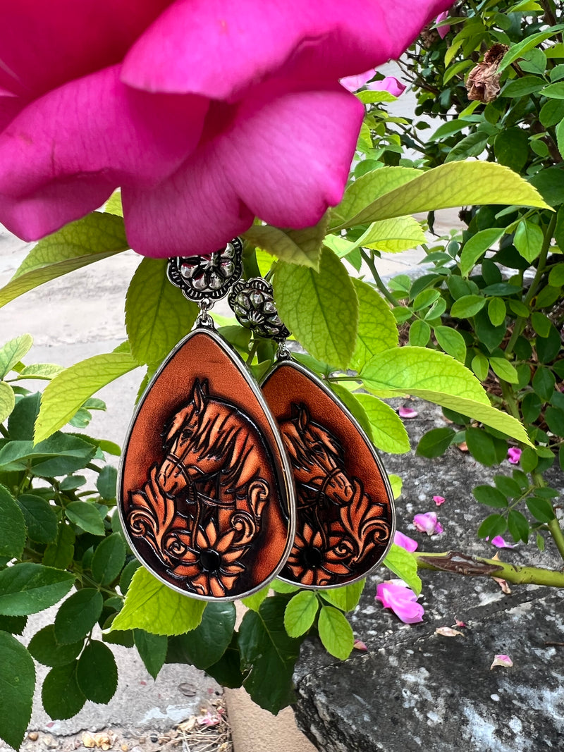 Bejewel your ears with these Saddle Up Earrings! Featuring a high polish silver, flower concho style, and a leather tooled floral & horse design, your outfit will be ready to ride the range in style! With a 3" dangle and a teardrop shape, these earrings will complete your western-inspired look! Yee-haw!