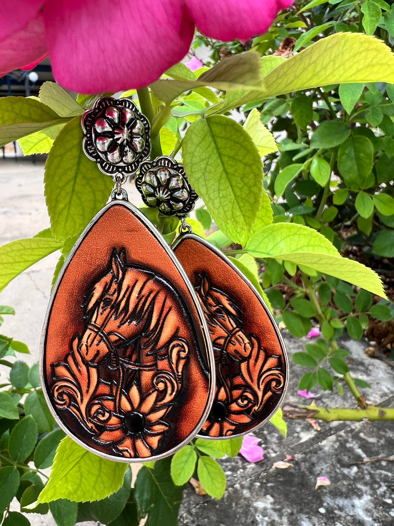 Bejewel your ears with these Saddle Up Earrings! Featuring a high polish silver, flower concho style, and a leather tooled floral & horse design, your outfit will be ready to ride the range in style! With a 3" dangle and a teardrop shape, these earrings will complete your western-inspired look! Yee-haw!