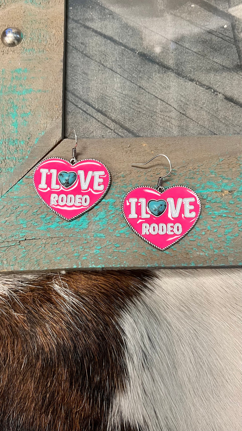 Make a fashion statement with these one-of-a-kind I Love Rodeo Earrings! Combining the subtle sophistication of high polish silver with the western-style of a turquoise heart stone and hot pink epoxy, these dangly earrings will show off your unique style, and give you a look that truly stands out in the crowd. Ain't no rodeo like the one you love!