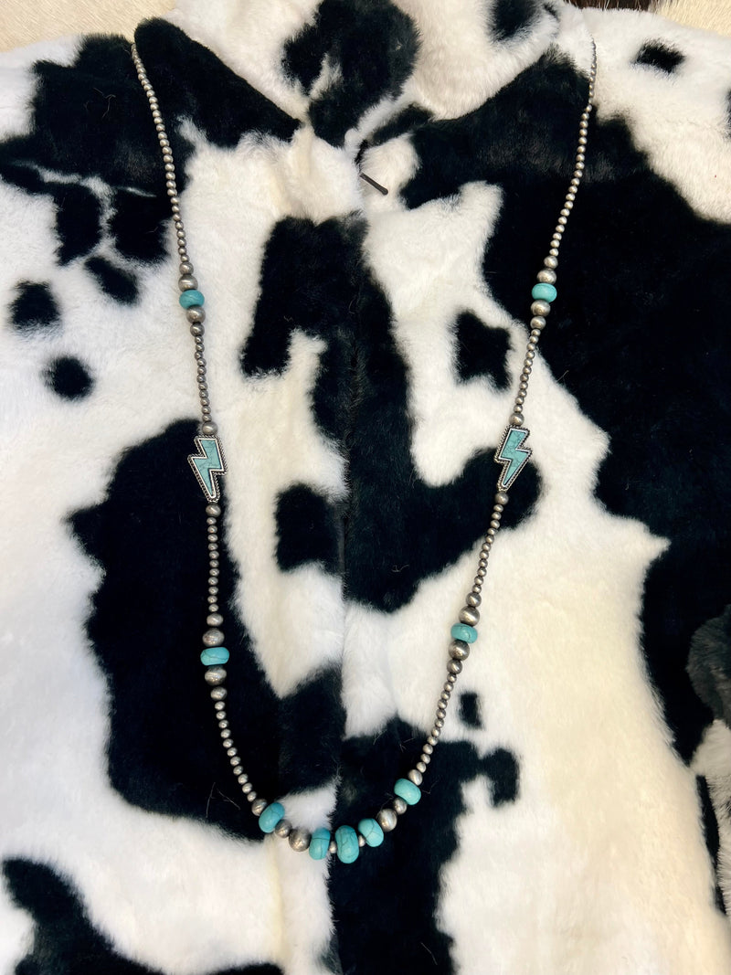 Two Color Choices: Turquoise or Pink  Look fierce and fabulous with this And The Lightning Strikes Necklace! Show off your wild side with its 36-inch length and 3-inch extender, high-polish cable texture, lightning bolt gemstone, and Western Navjao Pearls. Strike a pose and light up the night!