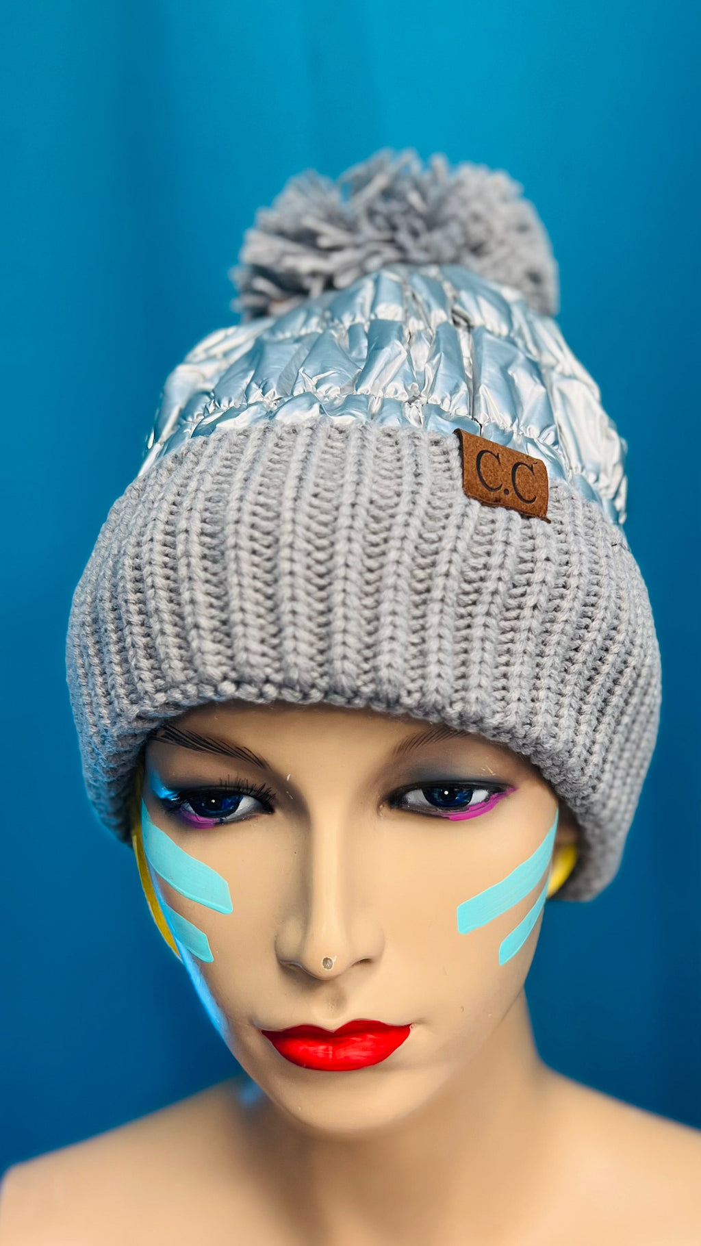 Stay stylish and warm this season with this unique, puffer silver foil C.C. Beanie. The intricate shiny material is truly flasy, and the plush pom pom on the top lends an exclusive, luxurious feel. Keep cozy but make a statement with this stylish beanie.  One size fits most.   Materials: Polyester, Acrylic
