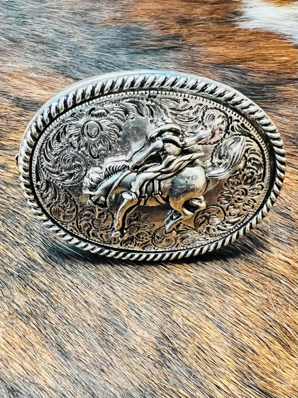 This Belt Buckle Pop Socket is a high-shine showstopper! You don't need to be a cowboy to rock this western concho style cell phone grip--just an eye for style. Featuring an oval shape, bucking horse with rider, and horse belt buckle design, you'll be ready to ride in style while securely holding your mobile device. Wowza, partner! 2 1/2"W X 1 3/4H.