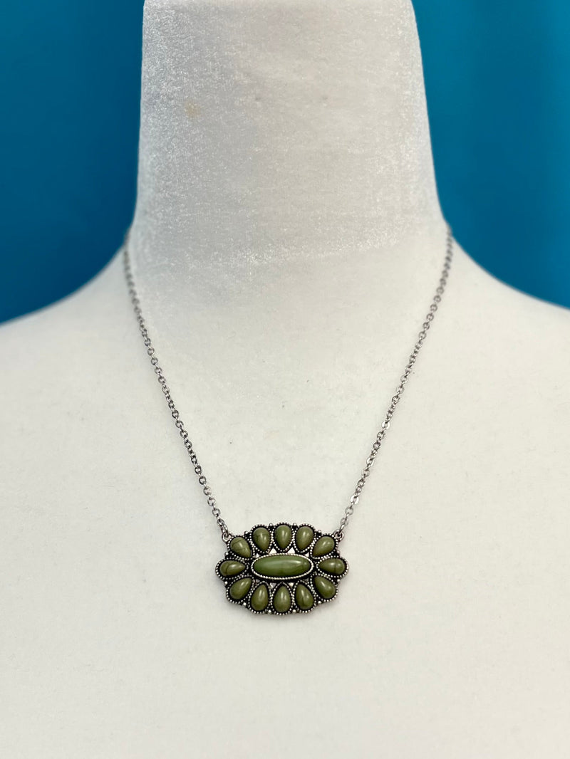 Our Olive Squash Necklace will have you looking stylishly wild. With its Western-inspired design and a round stone pendant accentuated with olive green stones, this silver necklace will add a fierce touch to your wardrobe. Not to mention, its charm size of 2", 18"chain with 3" extender will fit you perfectly. Get ready to hit the town in the ultimate fashion statement—nickle free!