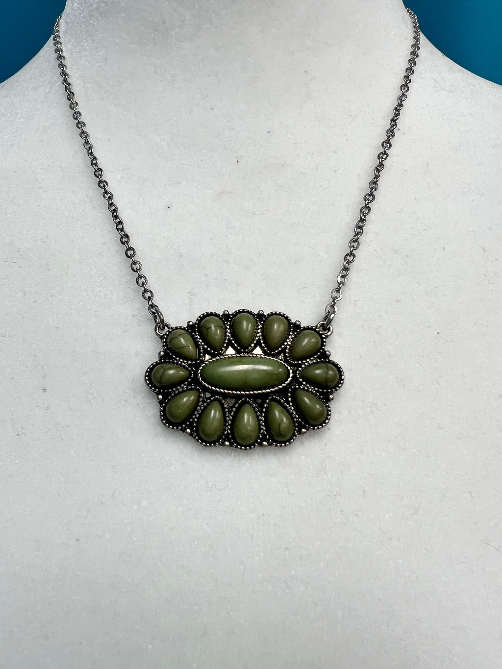 Our Olive Squash Necklace will have you looking stylishly wild. With its Western-inspired design and a round stone pendant accentuated with olive green stones, this silver necklace will add a fierce touch to your wardrobe. Not to mention, its charm size of 2", 18"chain with 3" extender will fit you perfectly. Get ready to hit the town in the ultimate fashion statement—nickle free!