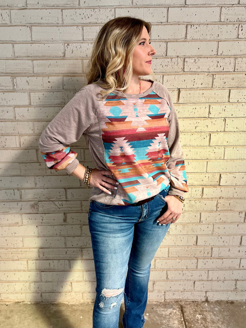 This Casually Southwestern Top will take you from the city to the desert in mocha-hued style! With a long sleeve design, terry cloth comfort, and Aztec print, you'll be ready to rock 'n' roll with a mire cut edge detailed scoop neckline. It's sure to be the perfect pick for your next southwestern adventure!   63% Polyester, 34% Rayon, 3% Spandex