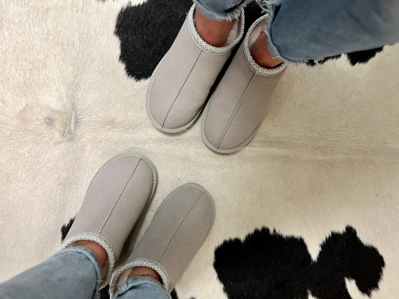 Snuggle into these UGGHH I Need These Slippers! The fur lined interior and ugg style design makes them a must-have, cozy-comfy addition to any lazy day. The grey hue and hard sole make them practical and sturdy, while the super comfort level makes them a treat for your feet.
