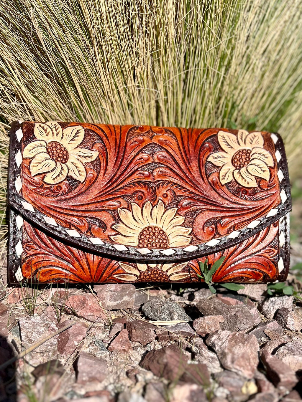 Introducing the Field of Sunflowers Wallet--the perfect companion for going out on the town! With an eye-catching floral tooling and a white whip stitch, you'll be stoppin' traffic all night. Brown leather and ready for a wristlet, crossbody, or wallet, this 4"X8" beauty has multiple credit card slots and compartments to keep your stuff safe and secure. So go ahead--make a style statement!
