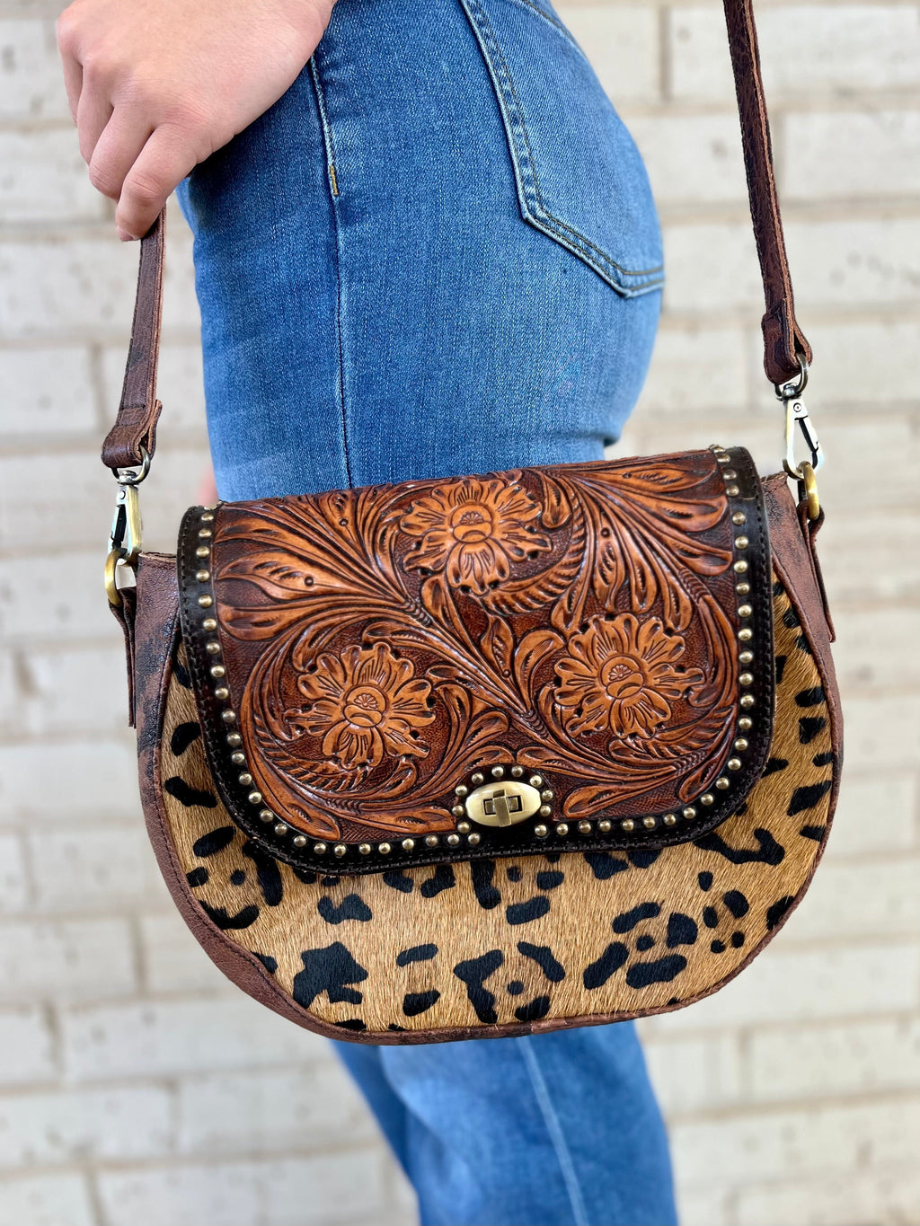 Make a statement with this unique leopard hair on hide bag. Crafted from tooled leather with floral tooled design and small nail head detail, it's as wild as it is stylish. With an adjustable/removeable strap, it can be a shoulder bag or clutch. Ready to hit the plains? Go wild with this must-have bag. 12" X 9" in size