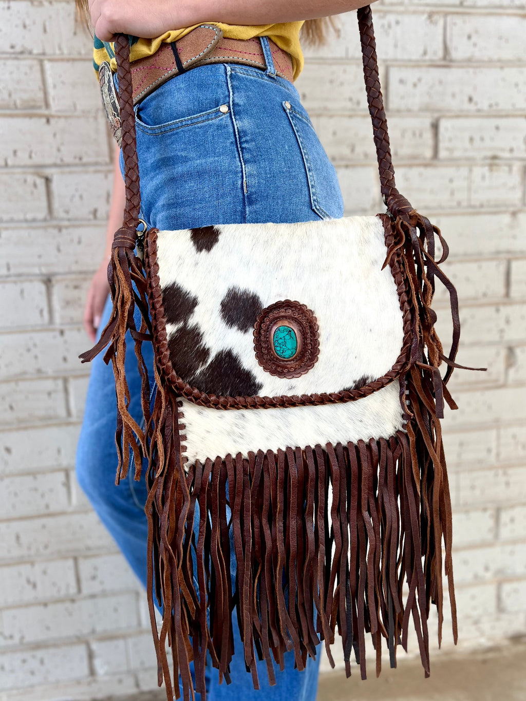 Take your style up a notch with the Turquoise Rock In The Herd Bag! This 10"X10" bag is made to impress with a 46" braided leather shoulder strap and 1.25" turquoise stone for a one-of-a-kind look. And snap front closure ensures your things stay secure. Show the herd what you're made of!