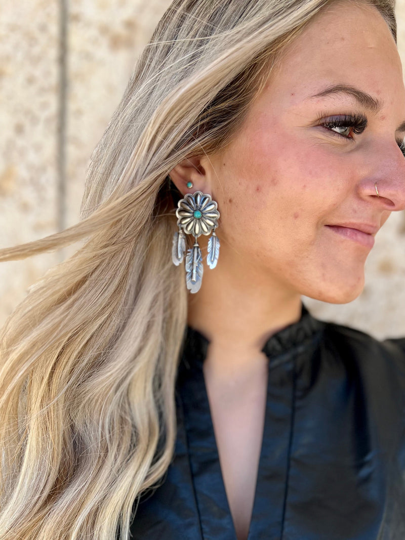 These T'aachill-t'a' Navajo Sterling Silver Earrings add a special touch of class to any ensemble. Handcrafted by Native Americans using genuine Navajo Sterling Silver, they feature a Genuine Turquoise stone and a unique 1" Concho design with 3 Authentic Sterling Silver dangle feathers. Perfect for any occasion.   Measure: 2 1/2" dangle  Suggested Retail:$400.00