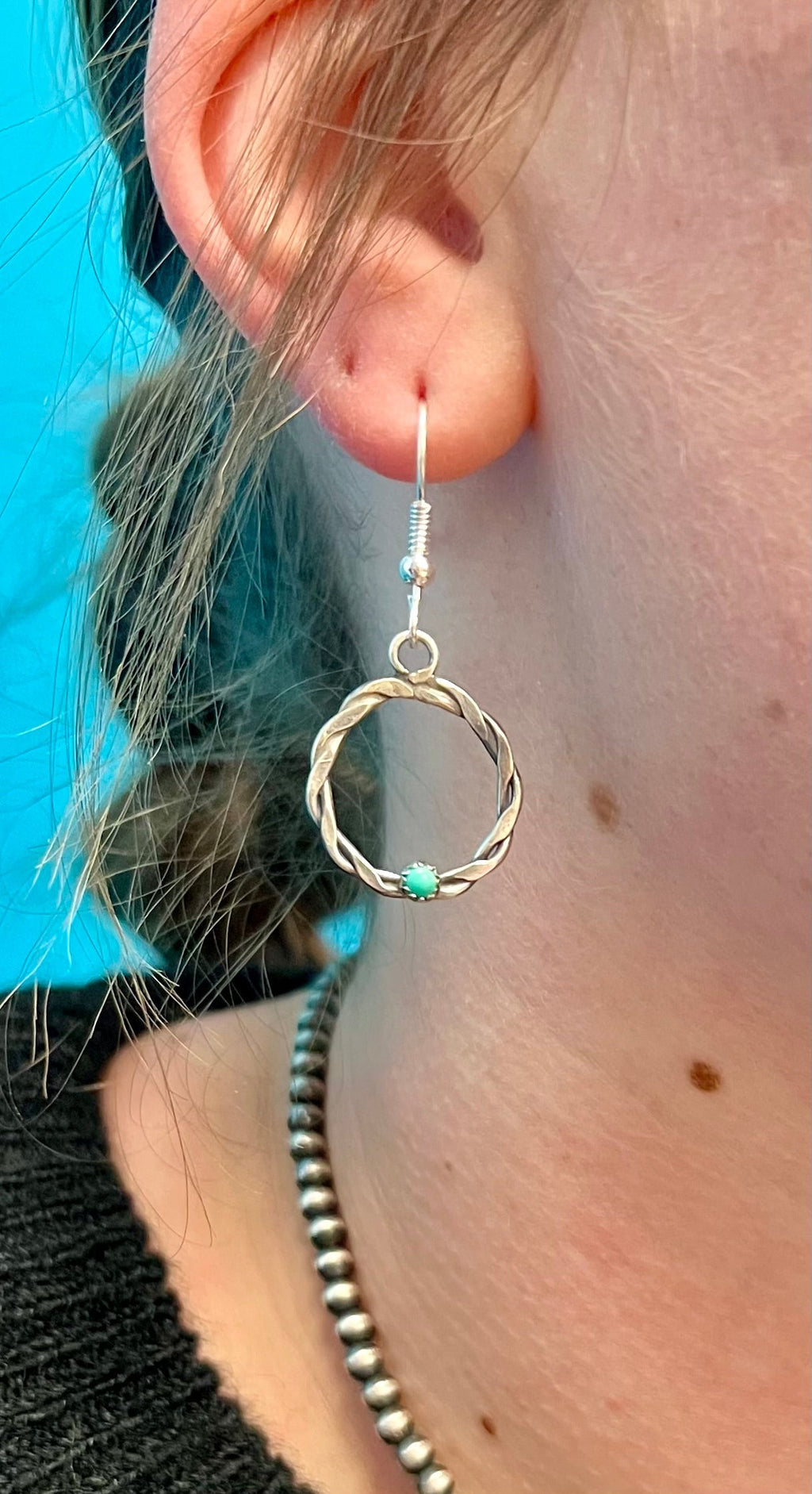 "Add a dash of Southwest charm to your style with Ropin' In Gallup Navajo Earrings. Crafted with authentic sterling silver and genuine turquoise stone, these earrings feature a unique twisted rope design and a classic fish hook for a playful dangle. Get ready to rock your outfits with this eye-catching accessory!"