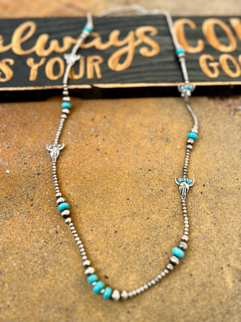"Add some unique style to your wardrobe with the It's All In Your Head Necklace. Featuring 36" Navajo pearls and turquoise beads, this necklace is adorned with silver cow skulls and a 3" adjustable lobster clasp. Perfect for those who don't take themselves too seriously!"
