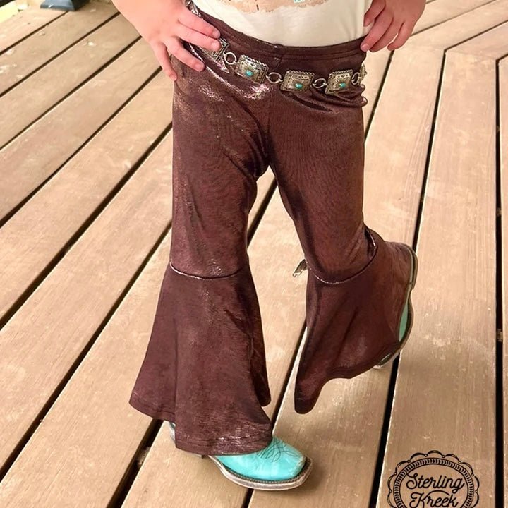 Be the bell of the ball wearing these TIME TO SHINE BELLS KIDS in metallic copper! These comfy bottoms have an extra stretchy waistband that's sure to rock your little one’s world. With TIME TO SHINE BELLS KIDS in copper, your kiddo will be shining bright in no time!  Kreek is wearing the XS.    I recommend sizing up if your kiddo is tall.      94% POLYESTER 6% SPANDEX