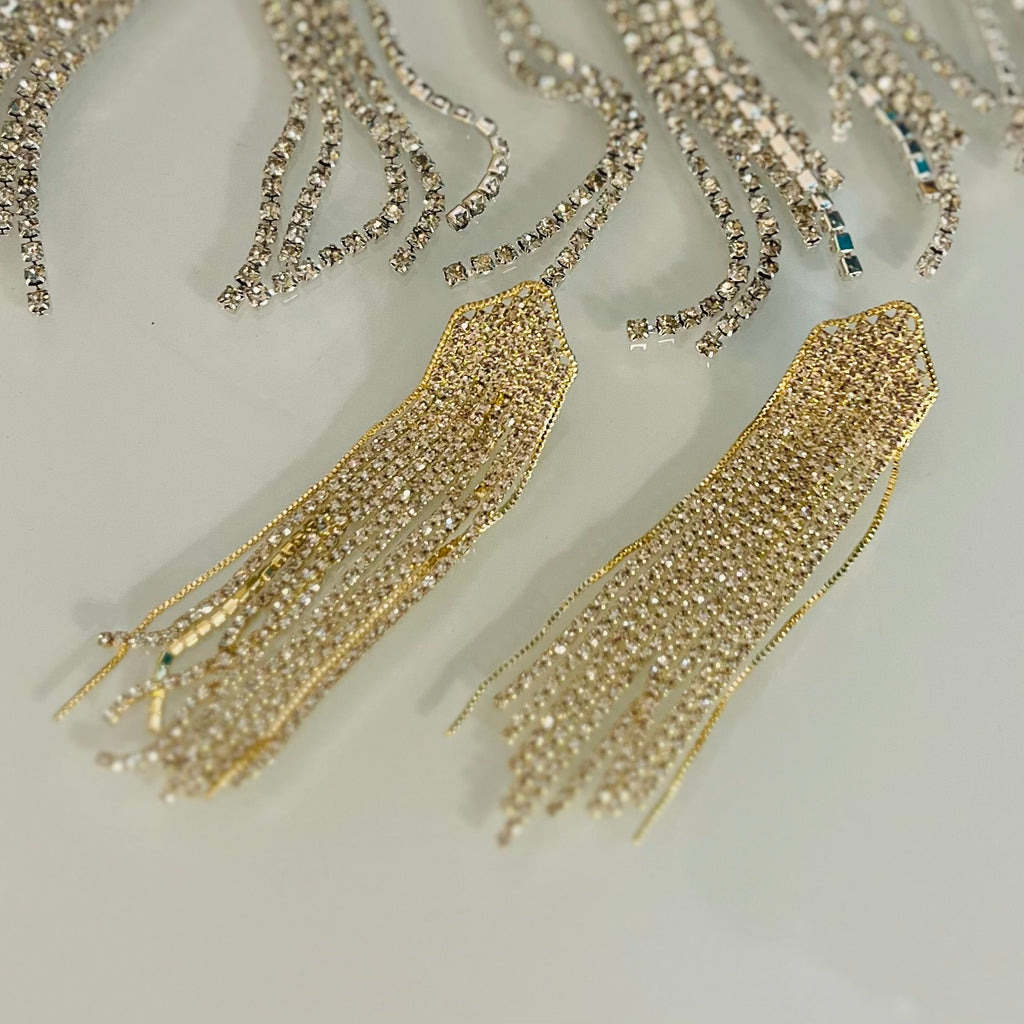 Elevate your look with these ultra-luxe Chandeliers In My Ears Earrings. These earrings boast an intricate design featuring either gold rhinestone or black rhinestone accents, and dangle gracefully from a post back closure. Perfect for any special occasion or night out.
