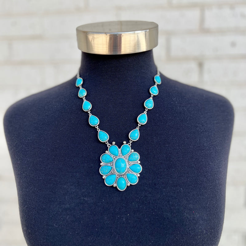 Adorn yourself with a timeless piece of jewelry. This elegant flower necklace is crafted with a 24" chain, a 3" adjustable lobster clasp, and a high-polished silver western-style concho flower pendant. Choose between two variants: turquoise or pearl. Get a classic look that endures.
