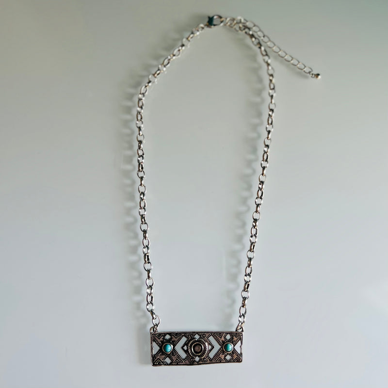 This "Stuck In The Middle" necklace is a showstopper for sure! The trendy western style features an aztec-inspired textured chevron cutout, all enhanced by sparkling turquoise stones across the rectangular bar shape. With a 16" chain and 3" adjustable lobster clasp, you'll always be bang on trend without being stuck in the middle!
