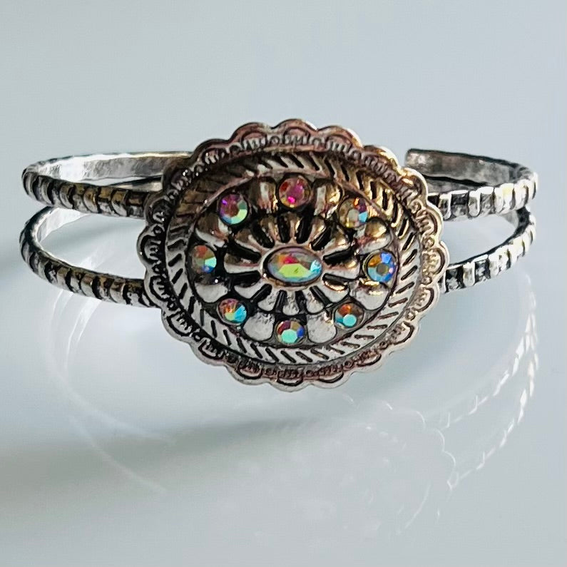 Bring your look to life with a flick of a wrist with this Rhinestone Cowgirl Cuff Bracelet. Its high-polished silver and western-style Aztec textured conch flower make it the perfect accessory for your next evening out. Plus, its flexible cuff and sparkling rhinestones bring shine that won't quit until the sun comes up! Get ready to yee-haw!