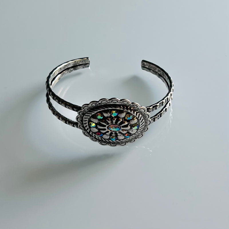 Bring your look to life with a flick of a wrist with this Rhinestone Cowgirl Cuff Bracelet. Its high-polished silver and western-style Aztec textured conch flower make it the perfect accessory for your next evening out. Plus, its flexible cuff and sparkling rhinestones bring shine that won't quit until the sun comes up! Get ready to yee-haw!