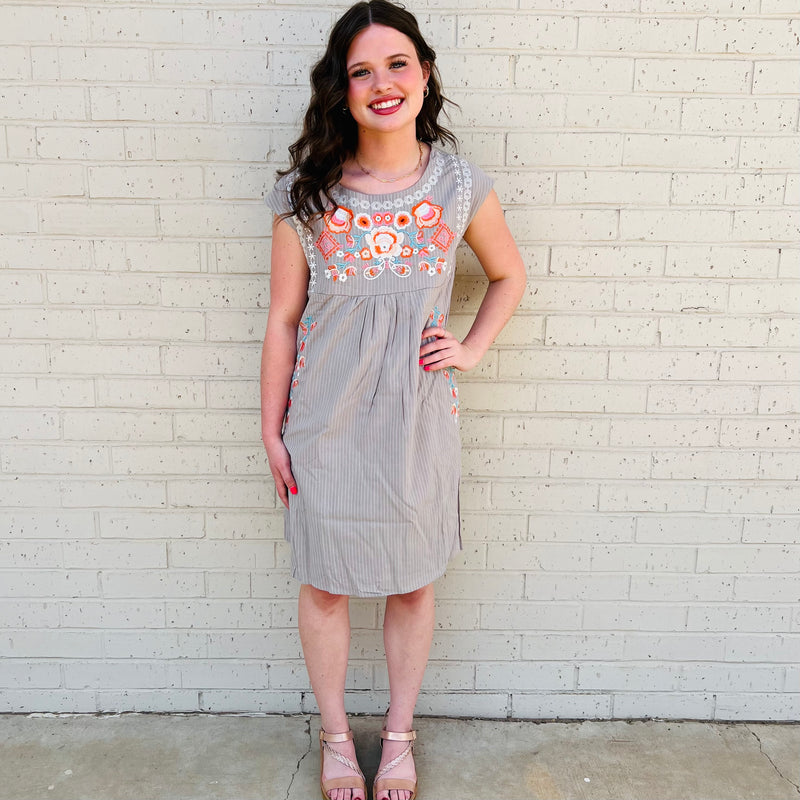 The Grey Annie Anne Dress is the perfect combination of sophistication and whimsy! With its sleek grey and white pin stripe and delicate floral pattern, you'll be sure to turn heads. The scoop neckline ensures comfort and ease of movement, and the back zipper closure adds the perfect touch of subtle flair.   50% Viscose, 50% Cotton