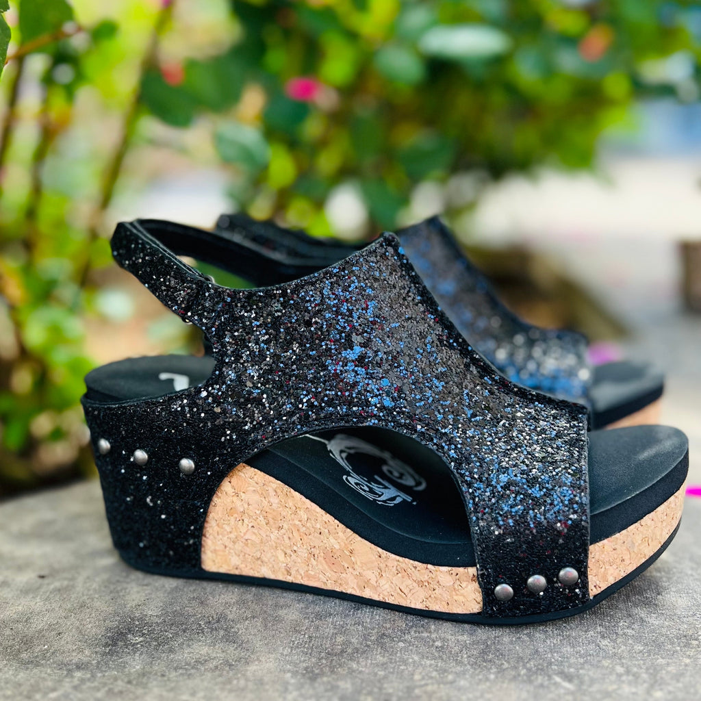 Step out in style with our Black Glittered Comfort Wedges. This eye-catching design features luxurious black glitter and a cork sole for added comfort. The sparkly straps and open toe add a touch of glamour, making these wedges perfect for a night out or special occasion.