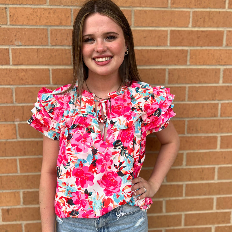 This Bushel and a Peck Top features a bright pink floral print and is made from 100% Polyester. It has a flutter sleeve and a rose ruffle detail that is sure to make a statement. Offering both style and comfort, it is the perfect addition to any wardrobe.