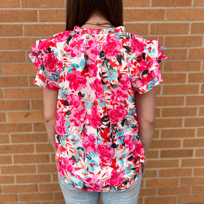 This Bushel and a Peck Top features a bright pink floral print and is made from 100% Polyester. It has a flutter sleeve and a rose ruffle detail that is sure to make a statement. Offering both style and comfort, it is the perfect addition to any wardrobe.