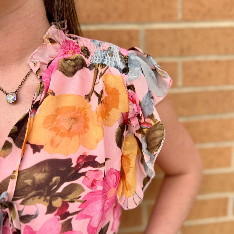 This Floral Vanity Blouse is perfect for summer days. With its pink floral print, tassel tie, and short sleeve cut, it's sure to make a statement. It has ruffle detailing around the neck and a notched V neckline for an elevated look. Made from 100% Polyester, it's lightweight and breathable.
