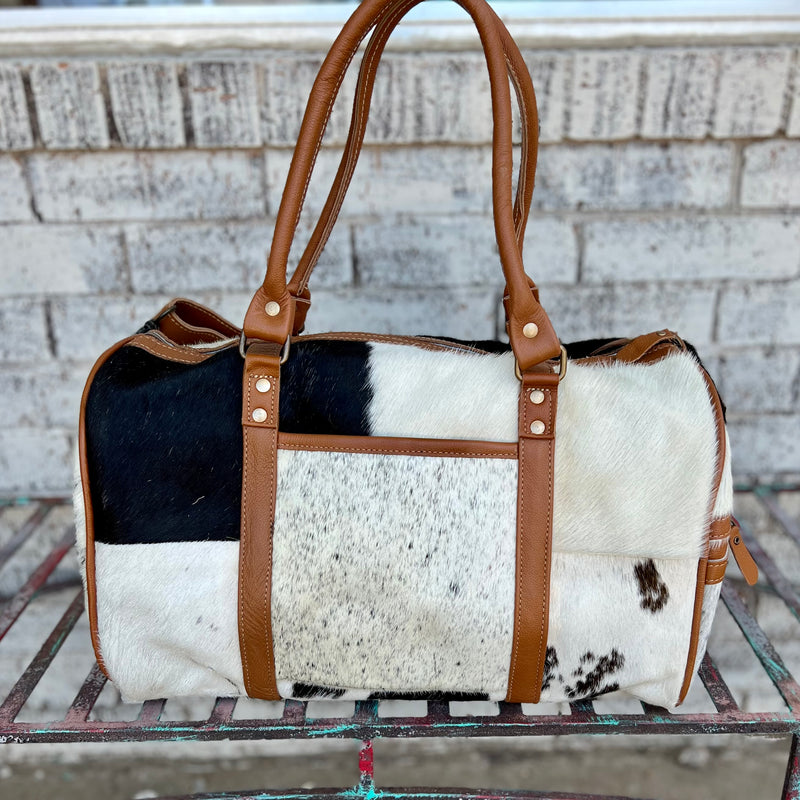 Hair on hide duffle bag with brown leather trim. Lots of pockets for organization. Outside zipper and pouch pockets, brass feet, and shoulder strap.  17"Wx10"Hx10"D