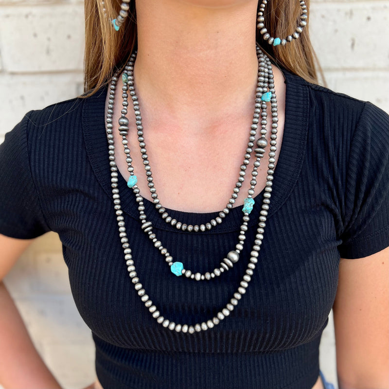 This elegant and timeless Between a Rock and a Hard Spot Necklace is perfect for those who value classic sophistication and style. Its triple-layered silver beaded design with turquoise stone accents is sure to add a luxurious touch to your look. With a length of 24" it is perfect for any special occasion.