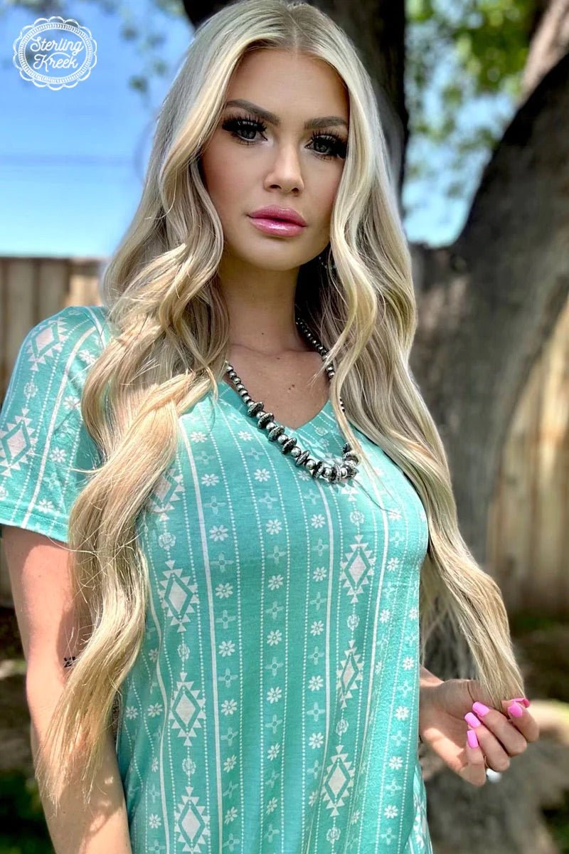 Turquoise and white aztec print dress. T-shirt dress with western print. Knee length t-shirt dress. V-neck shirt dress. Women's western wear. Women's western fashion. Western boutique. Online boutique. Small business. 