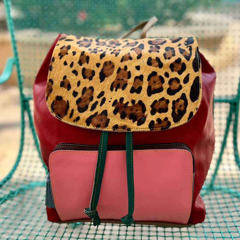 Add a bit of sass and spunk to your wardrobe with this Sosie Leather Drawstring Backpack! Its bold and beautiful multi colored leather with leopard print hair on hide fold over flap are sure to turn some heads. With a spacious 12"W X 14"H main compartment and a convenient 8"W X 6"H front zipper pocket, this bag will be sure to fit all of your stuff! Get ready to work it and strut your stuff!