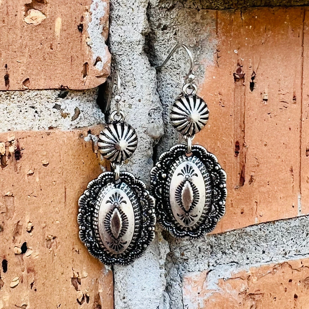These exquisite Mother May I Earrings make for a perfect addition to your evening wardrobe. Crafted of silver stamped metal and concho style, they are delicately suspended from a 2" dangle, lending an air of sophistication to any ensemble. The round shape adds a subtle touch of glamour to your look.