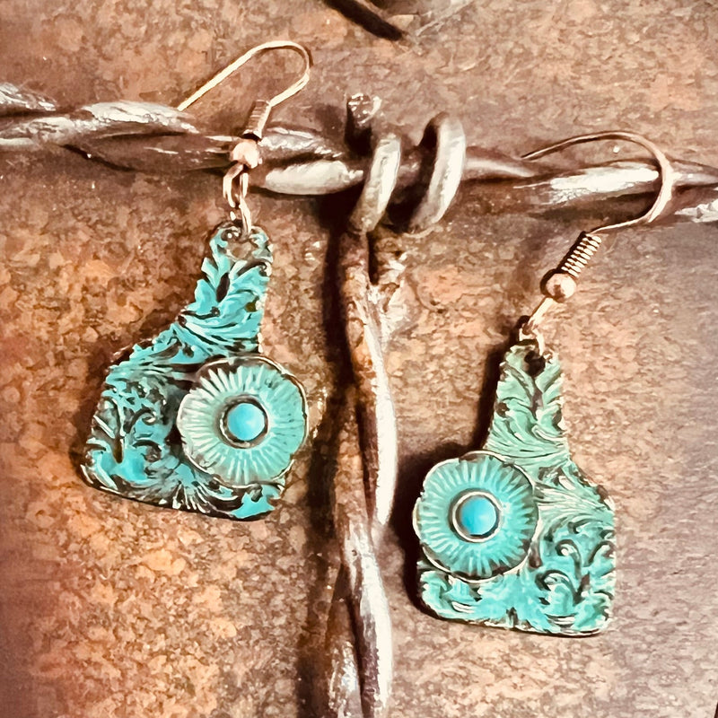 Exquisite and eye-catching, these Perfectly Tooled Patina Tag Earrings bring a touch of sophisticated style to any ensemble. Crafted from copper and adorned with a beautiful pattern of floral tooling, each earring is topped with a patina-covered cattle tag adding a hint of rustic flair. Subtle yet stylish, these earrings are sure to be a standout piece in your jewelry collection.