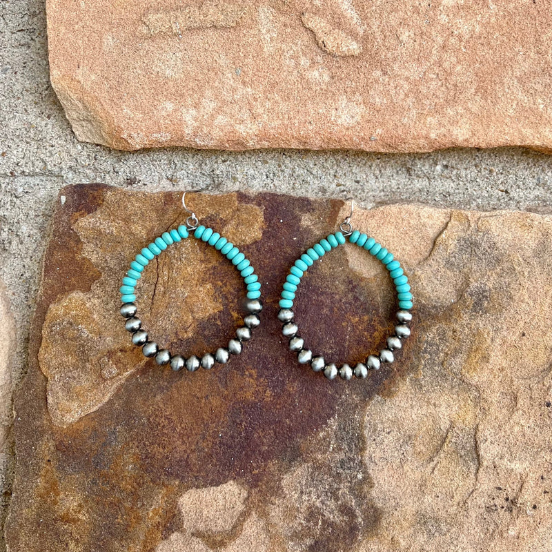 These Hoop Me in Turquoise Hoops are a chic and sophisticated addition to any outfit. Crafted with turquoise beading and small faux navajo pearls, these earrings add a touch of elegance and glamour to any look. With a 2.5" dangle and fish hook, these hoops are sure to become a timeless classic.
