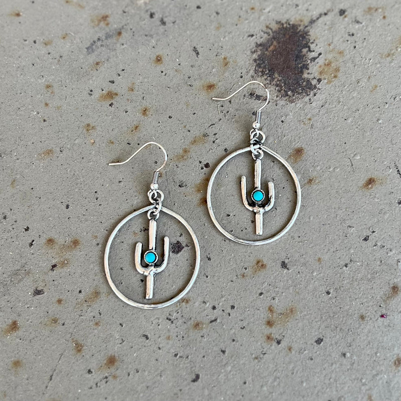Complement your chic, western style with our Stuck Around Here Earrings. These eye-catching accessories feature silver cactus and turquoise stone dangles on stunning, gold hoop backings. A fish hook closure ensures a secure fit, while the earrings hang 2” in length. Strut around with effortless elegance wearing these memorable earrings.