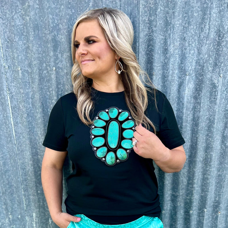 This STREETS OF TURQUOISE TEE will have you looking like a million bucks! Featuring a black tee with a sparkling turquoise sequin concho design in the middle, it's the perfect way to dress up a casual look. Yee-haw!  60% polyester 35% rayon 5% spandex