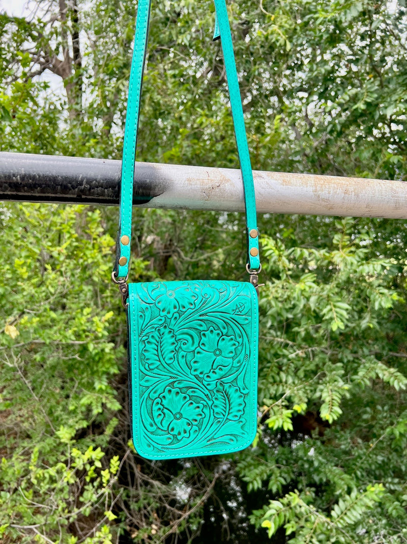 Introducing the Calling Me Turquoise Darling Messenger Bag, the epitome of luxury and sophistication. Crafted with genuine leather and a turquoise floral tooled pattern, it's sure to make a statement in any setting. The 50" adjustable/removeable strap ensures it's comfortable to carry, and the large basket weave tooled pattern on the bottom and back side adds an extra special touch. 5"W X 7"H