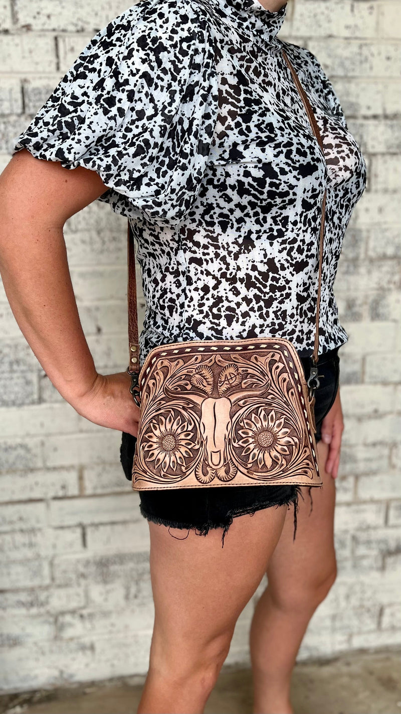 Discover the darling, western inspired beauty of this Longhorn Country Tooled Leather Bag . Crafted with an exquisite floral tooled pattern on the front with a Tooled Longhorn in the center and white buck stitch trim,  this piece adds a subtly sophisticated air to any look. The gorgeous tooled sunflowers make this bag pop. With a generous 9"W X 7"H size and a 50" adjustable and removable strap, this stunning bag offers convenience and effortless style.