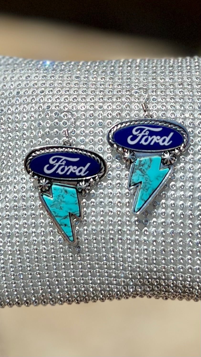 Express your love of classic American brands with these Ford Earrings! Featuring a western-style concho in a high-polish silver finish, plus a thunderbolt and Ford logo for the perfect combination of style and spirit. Hang 'em up with the cable-textured fish hook and show off that unmistakable dangle!