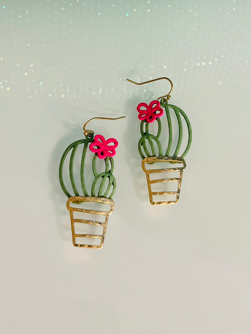 Stand out with these whimsical yet chic Potted Cacti Earrings - perfect for wearing on sunny days and summer nights alike! These earrings feature a lush green cactus housed in a gleaming gold flower pot, with a rubber-coated fish hook and 2" of length. Add a unique touch to any ensemble with these fashionable plant-inspired earrings!