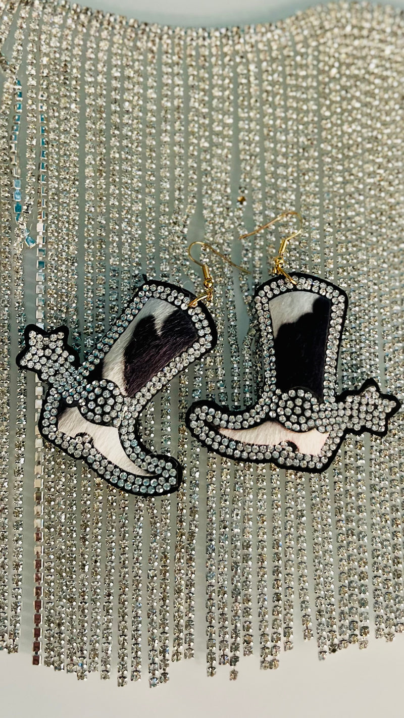 Giddy up with our Puffed Up Boot Earrings! Crafted from black & white cow fur print with rhinestone inlay on the spur and spur strap, these unique accessories will spruce up any outfit. Add that final touch with the shimmering fish hook and puffed design, matched perfectly with a wink and a smile. Ride off into the sunset! 2" in length
