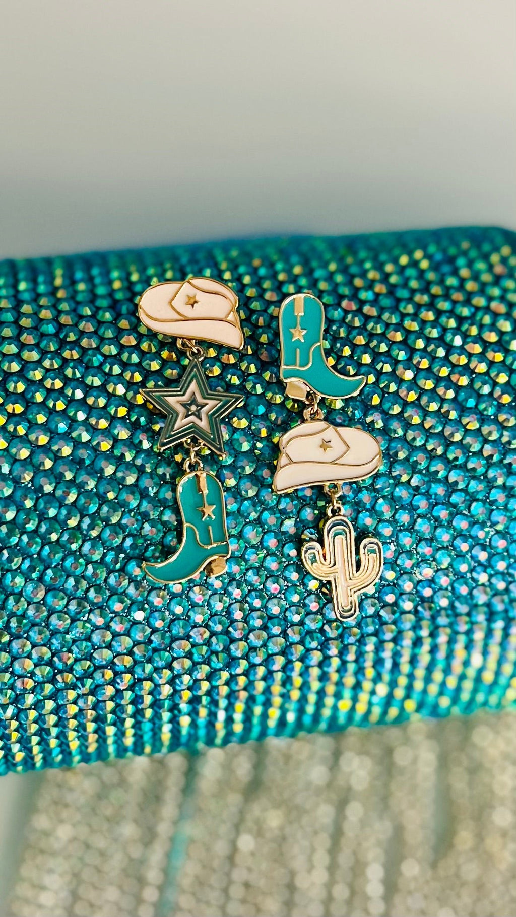 Add some southwestern flavor to your look with these eye-catching Dangling Western Turquoise Earrings. These 'statement makers' feature an eclectic mix of turquoise, white and gold drop designs in a western theme - perfect for showing off your style! Just don't forget to keep a tight grip on 'em when you're out 'ridin' the range'. Yee-haw! 2" in length