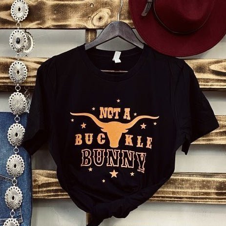 Feel the wild spirit of the rodeo with the Not A Buckle Bunny Tee! This stylish black crew neck is perfect for modern cowgirls and cowboys, featuring a classic and soft western-style graphic. Get ready to rope 'n ride in this stylish and unique piece of rodeo-inspired fashion!   