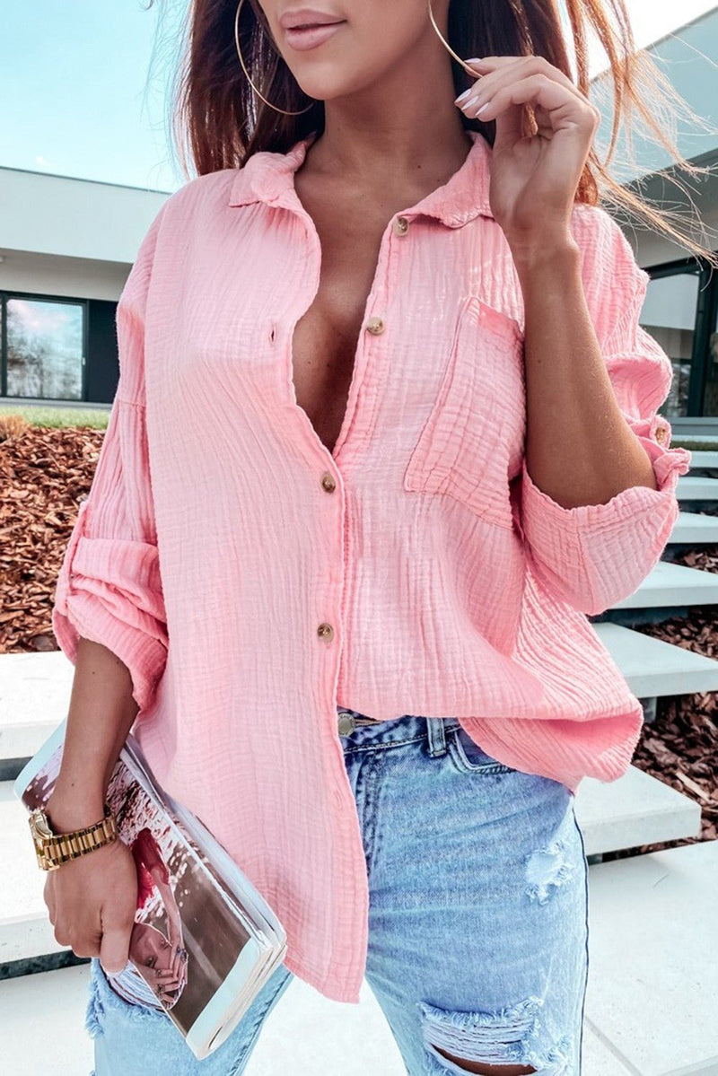 Pep up your wardrobe with this cheerful pink crinkle top! Its roll tab sleeves give a cutesy 'Barbie' touch, while the button-up front ensures you can ramp up the glamour - or keep things low-key. Plus, it's the perfect way to add a dash of fun to your look!